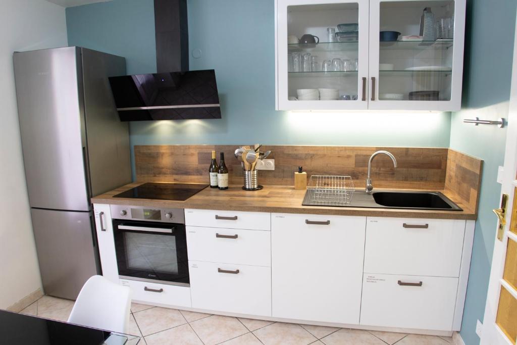 a kitchen with white cabinets and a sink and a refrigerator at Kasa Jura 2 - Centre ville - Proche pistes de ski in Saint-Claude