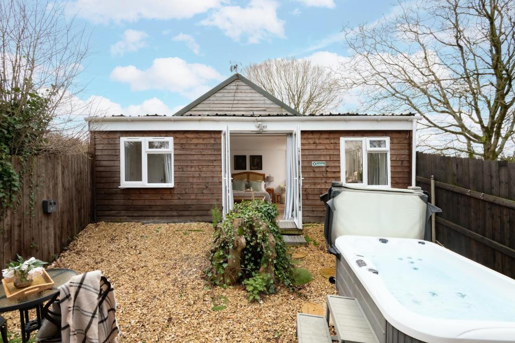 une petite maison avec une baignoire dans une cour dans l'établissement Meadow - Woodland Cottage with Private Hot Tub, à Blandford Forum