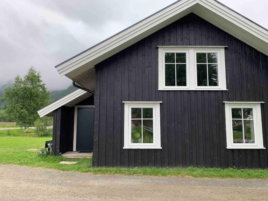 una casa negra con dos ventanas y un garaje en Lofoten- Feriehus Fjøsen, en Ørsvåg