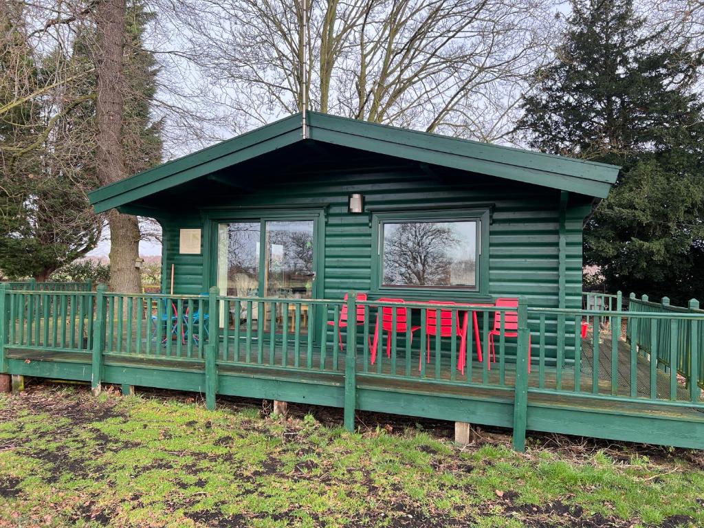 una casa verde con dos sillas rojas. en Holme Woodmans Lodge en Holme