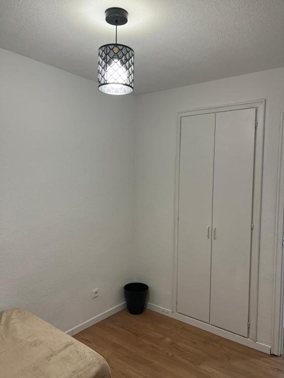 um quarto branco com uma cama e um candeeiro em Habitación en Madrid em Madri