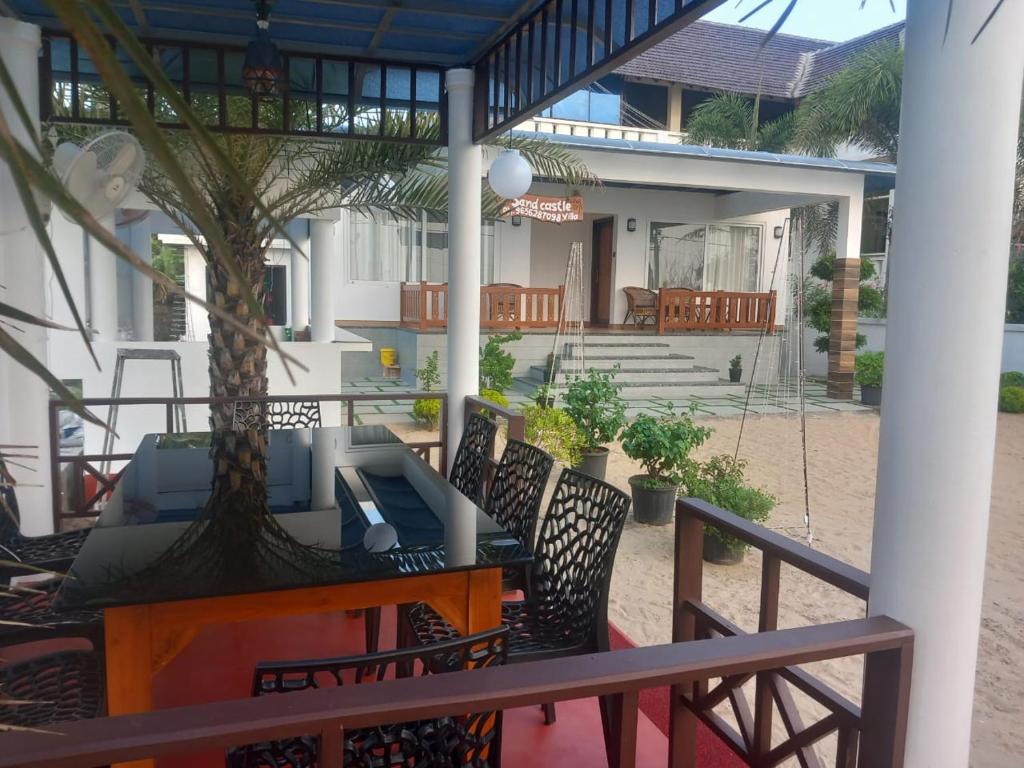eine Terrasse mit einem Tisch und Stühlen sowie ein Haus in der Unterkunft Sandcastle in Kochi