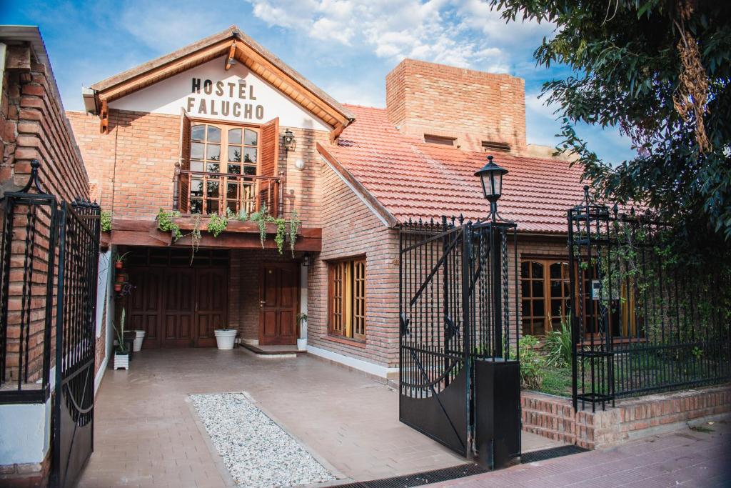 un edificio de ladrillo con una puerta delante de él en Hostel Falucho en Capilla del Monte