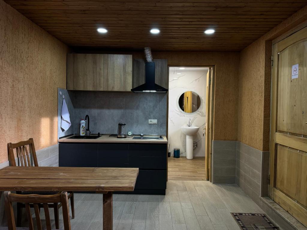 a kitchen with a table and a sink and a toilet at cozy apartments kazbegi in Stepantsminda
