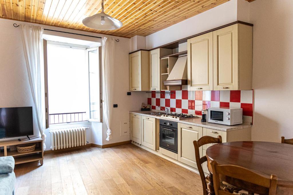 a kitchen with white cabinets and a table and a window at Magico Loft nel Centro Storico in Toscolano Maderno