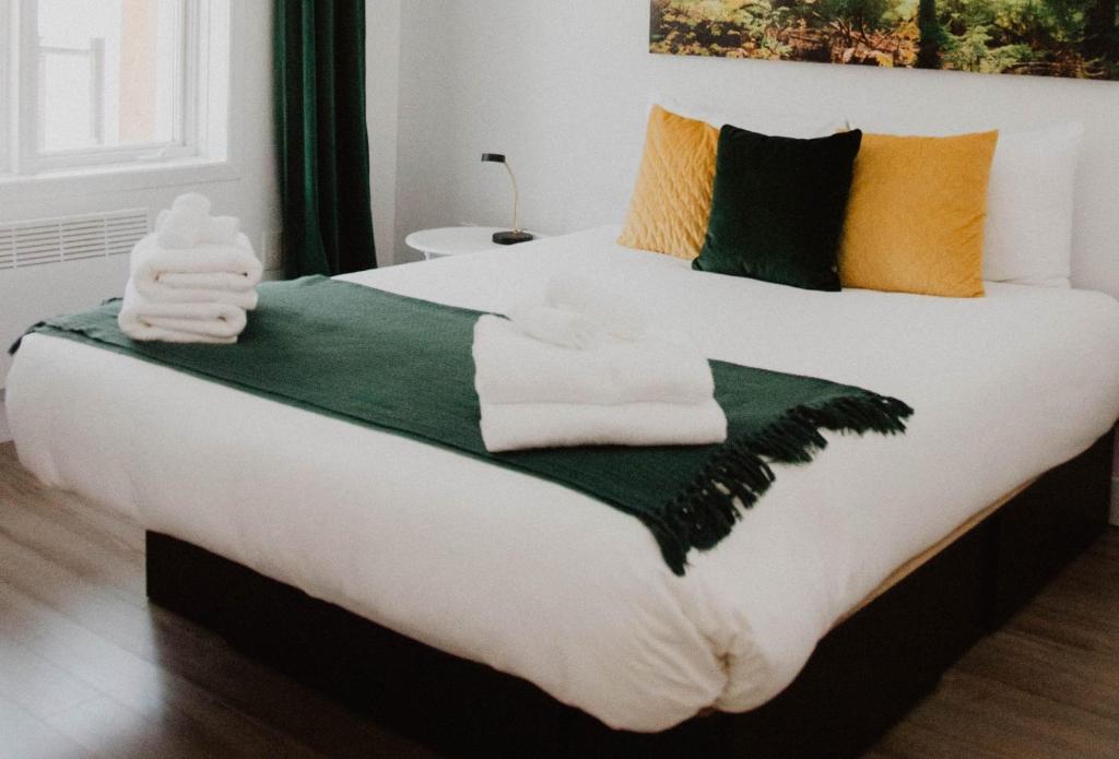 een slaapkamer met een groot bed met groene en gele kussens bij Suite 204 - Destination Mont-Orford in Magog-Orford