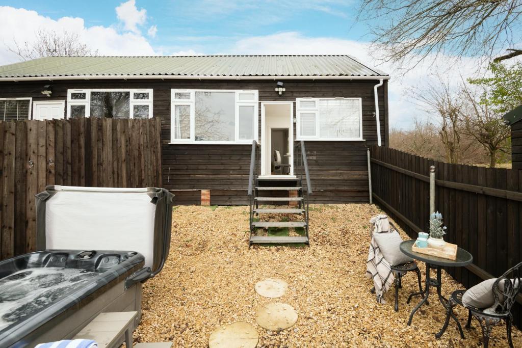 a small house with a fence and a backyard at Dreamwood - Woodland Cottage with Private Hot Tub in Blandford Forum