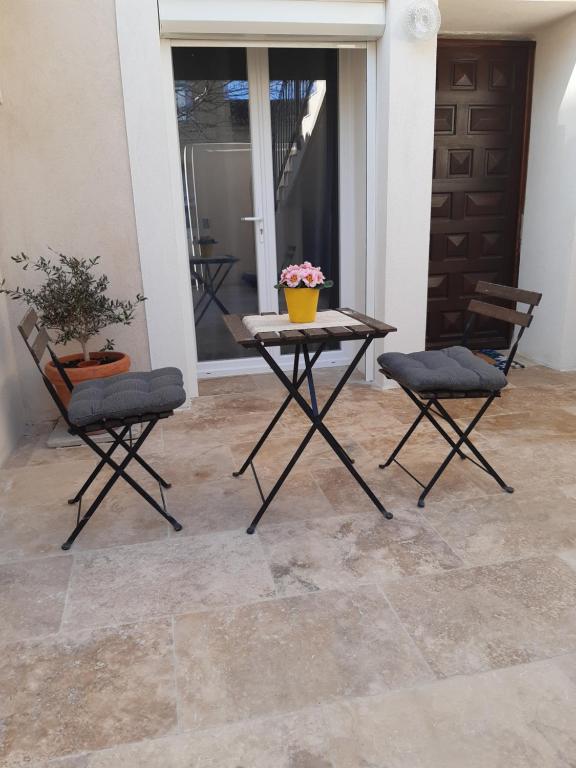 een patio met 2 stoelen en een tafel met bloemen erop bij Le gîte d'églantine in Eyguières