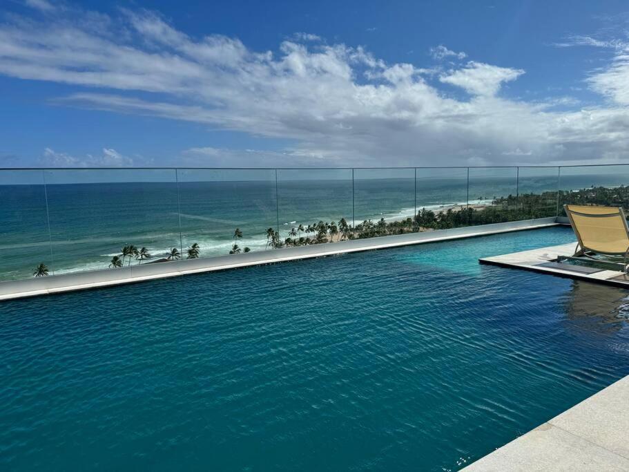 a swimming pool with a chair next to the ocean at 1/4 sala mobiliado, completo, em Stella Maris/Salvador in Salvador