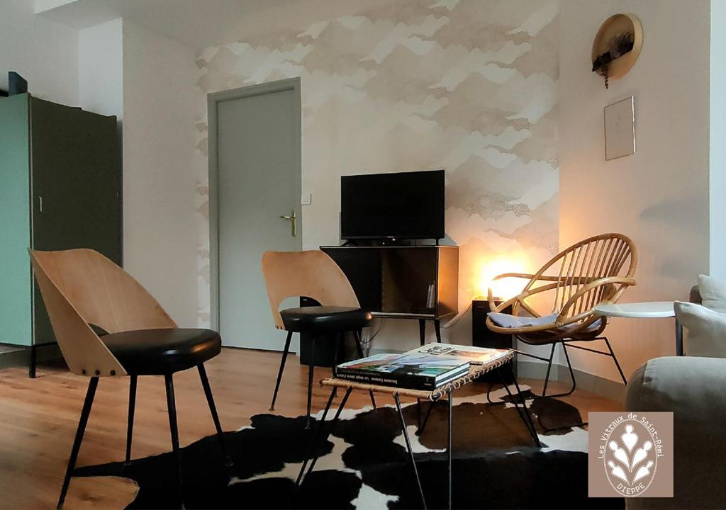 - un salon avec des chaises, une table et une télévision dans l'établissement Les Vitraux de Saint Rémi, à Dieppe