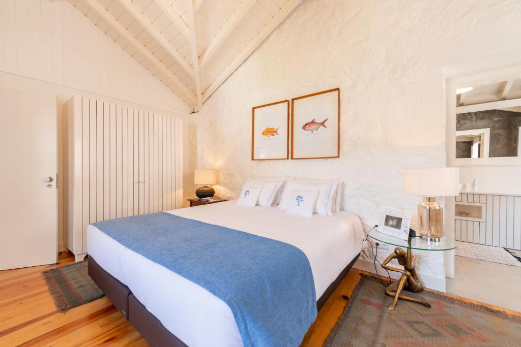 1 dormitorio con 1 cama blanca grande con manta azul en T1 Casa das Pereiras, en Calheta de Nesquim