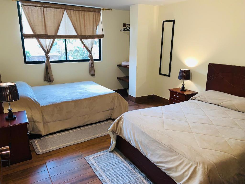a bedroom with two beds and a window at Hostal Casa San Fernando Tumbaco in Quito