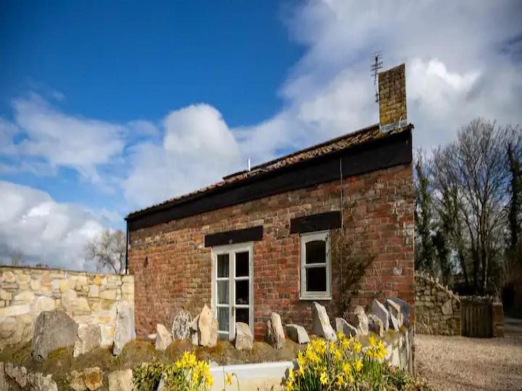 a brick building with a window and a stone wall at Pass The Keys Wilf's Barn, Wedmore a romantic cottage for two in Wedmore