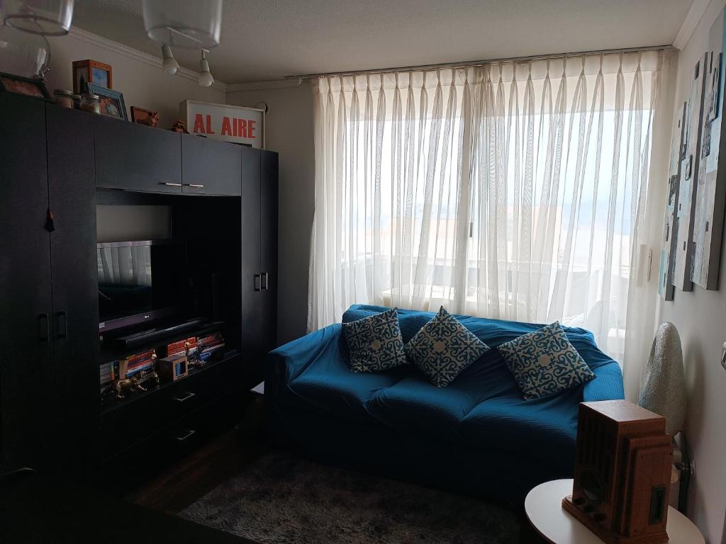 ein Wohnzimmer mit einem blauen Sofa vor einem Fenster in der Unterkunft Departamento Aquamar in Viña del Mar
