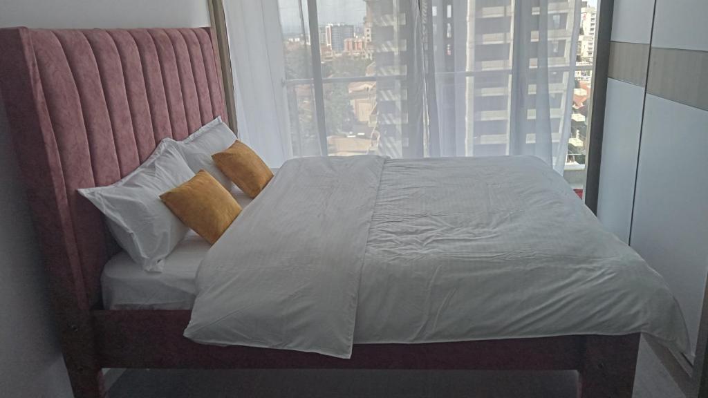 Cama en habitación con ventana grande en Lovella Suites Gold Park, en Nairobi