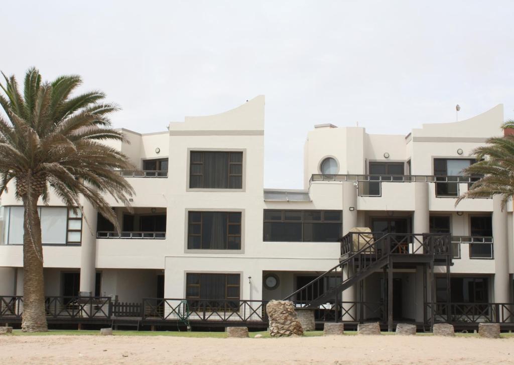 a building with a palm tree in front of it at Erf Three Seven Eight Langstrand Self-Catering in Langstrand