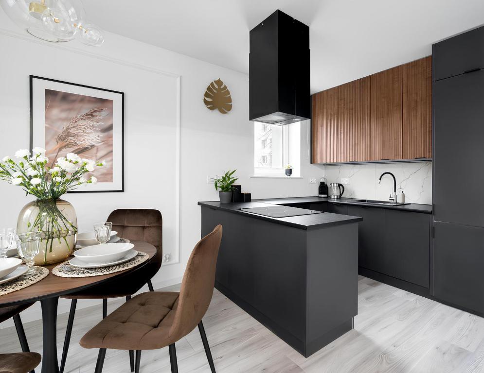 une cuisine avec des armoires noires, une table et des chaises dans l'établissement Flatbook - City Center Apartments Kamienna Grobla, à Gdańsk