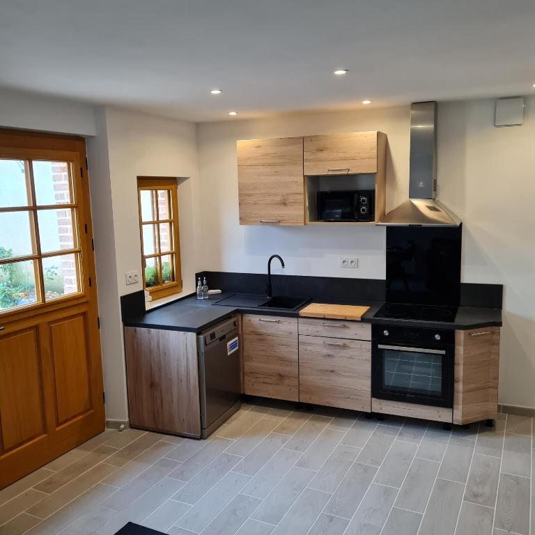 une cuisine avec des armoires en bois et un comptoir noir dans l'établissement Gite Les Mouettes Blessées, au Crotoy