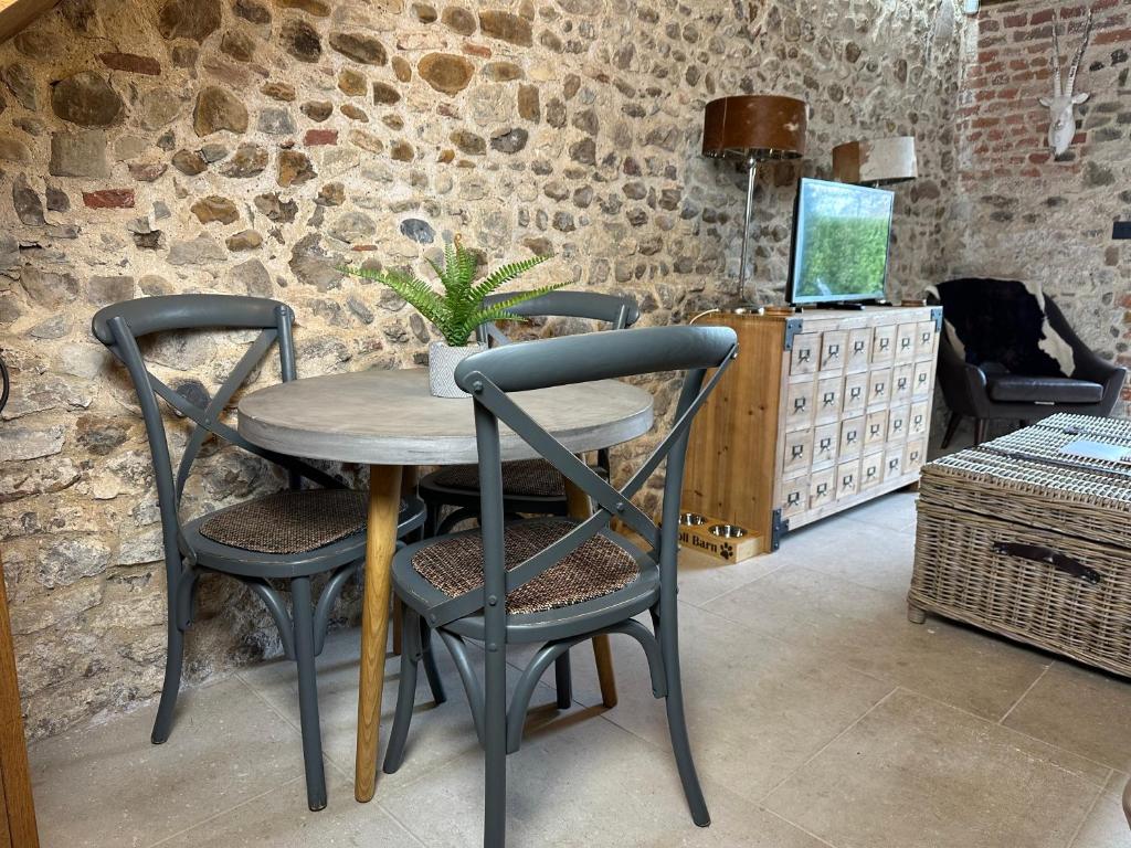 a table and chairs in a room with a stone wall at Toll Barn, St Osyth Priory in Colchester
