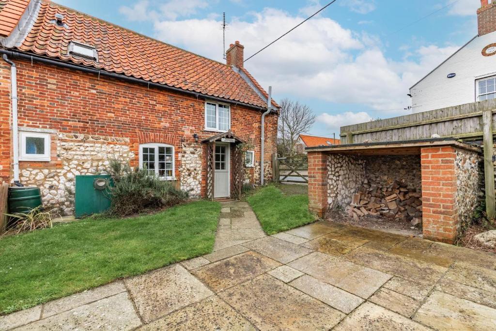 a brick house with a pathway leading into a yard at 1 Ruscon Cottage in Brancaster
