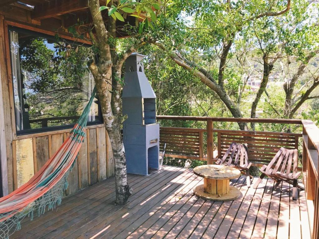 a deck with a hammock and a bird house at Pescador de Sonhos in Praia do Rosa