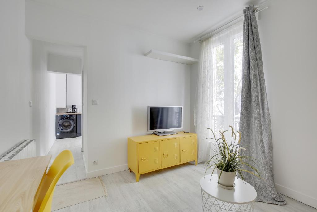 a living room with a tv and a yellow cabinet at Chic studio near Paris in Colombes