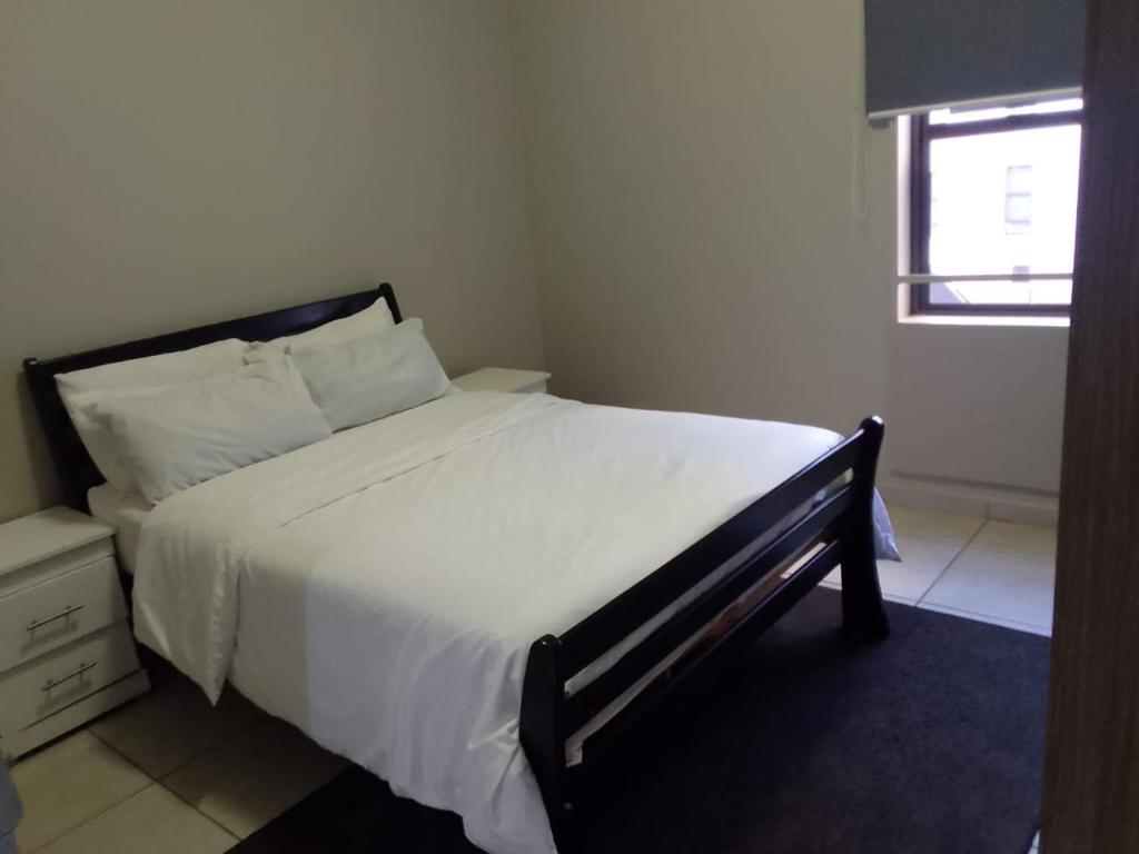 a bedroom with a large bed with white sheets and a window at KellyCh Rosyka in Johannesburg