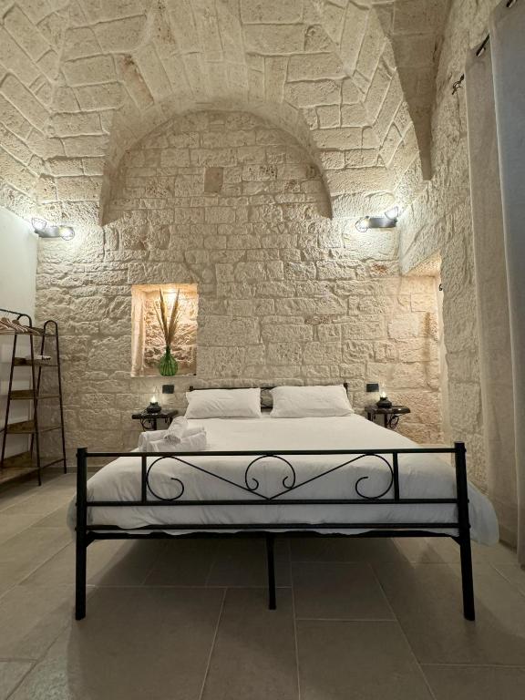 a bedroom with a bed in a stone wall at Le Pietre Apartments in Ostuni