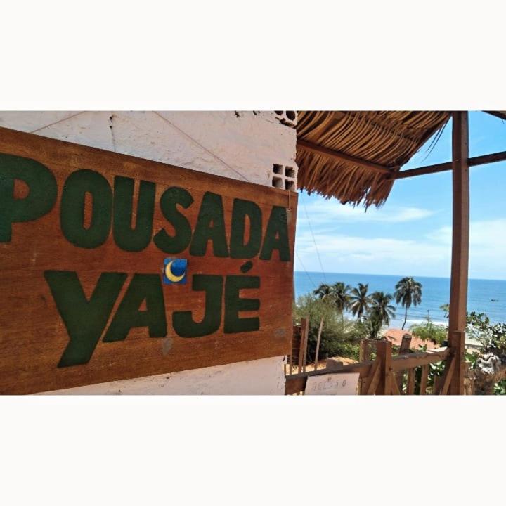 a sign on the side of a building next to the ocean at Pousada Yajé in Ponta do Mel