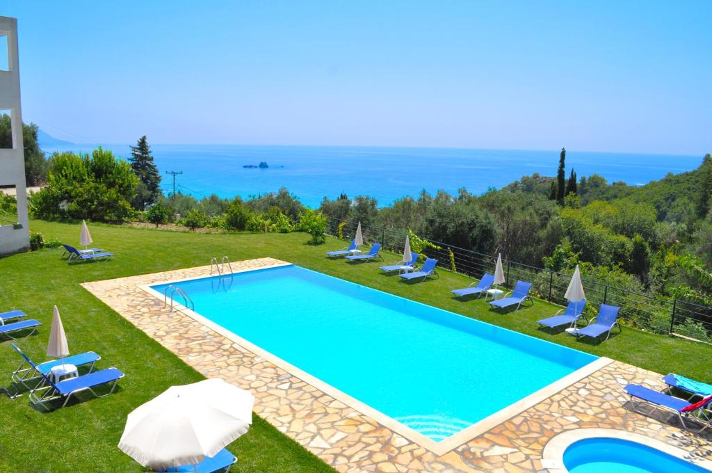 una piscina con sillas y sombrillas y el océano en Apartments and studio with swimming pool and Sea View in Pelekas Beach, Corfu, en Pelekas