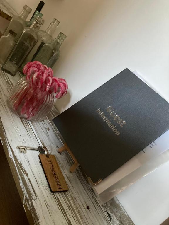 a book and a vase on a table with bottles at Lime Tree Cottage in Tillingham