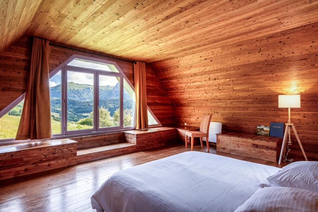 L'Impradine, grand gîte vue et nature splendides في Le Falgoux: غرفة نوم بسرير ونافذة كبيرة