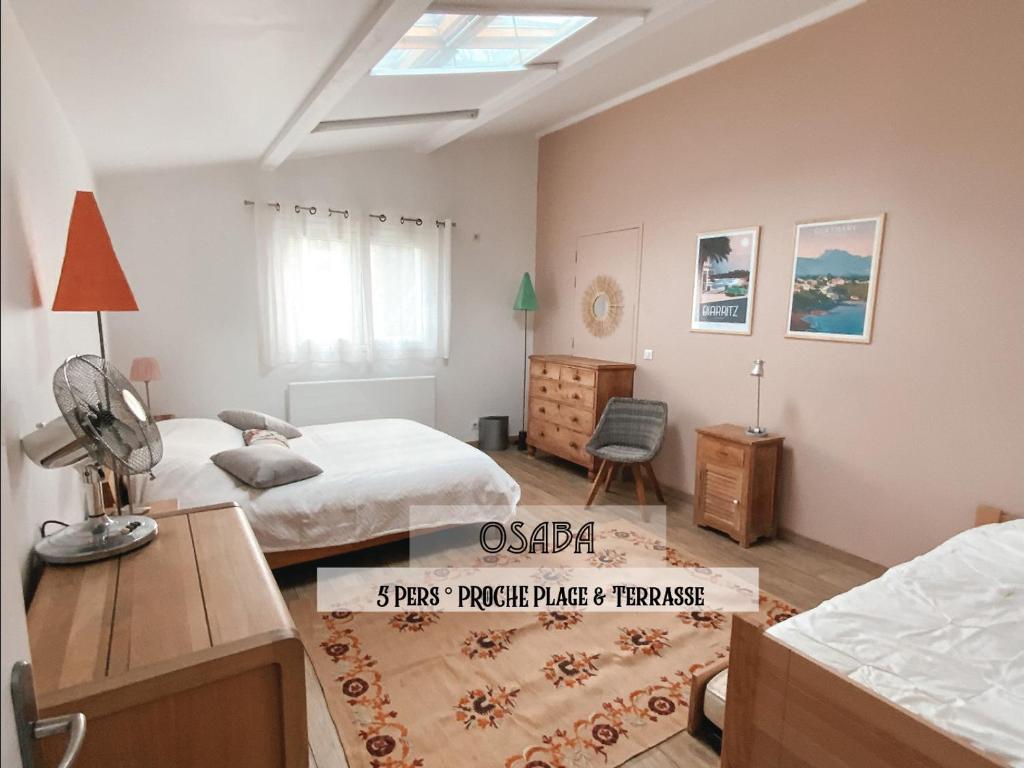 1 dormitorio con 2 camas y escritorio con ventilador en Osaba proche plage et terrasse, en Biarritz