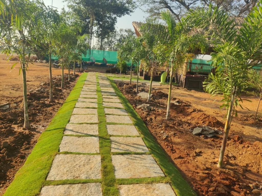un sentiero in un giardino con palme di Goutham Guest House And Restaurant Hampi a Hampi