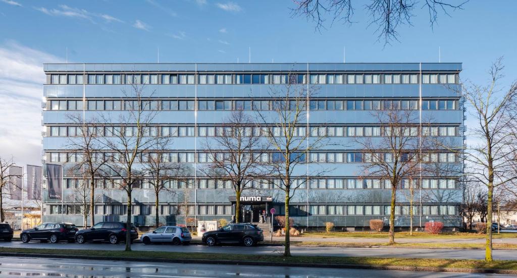 Un grand bâtiment avec des voitures garées devant lui dans l'établissement numa I Viktoria Apartments, à Munich