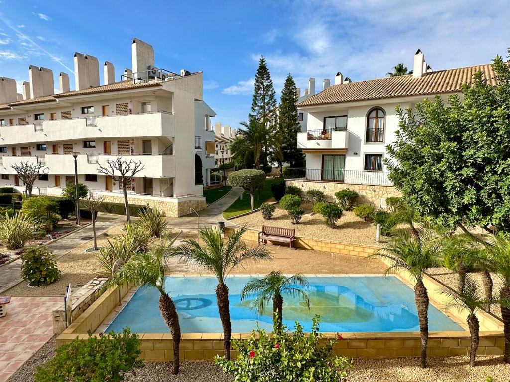 un immeuble d'appartements avec piscine et palmiers dans l'établissement Bonito Apartamento Con Piscina y Jacuzzi, à L'Alfàs del Pi
