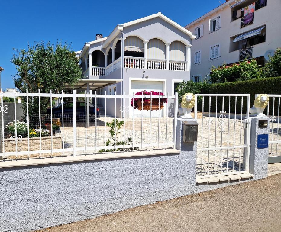 a white fence in front of a building at Cosy villa near the beach in Zadar