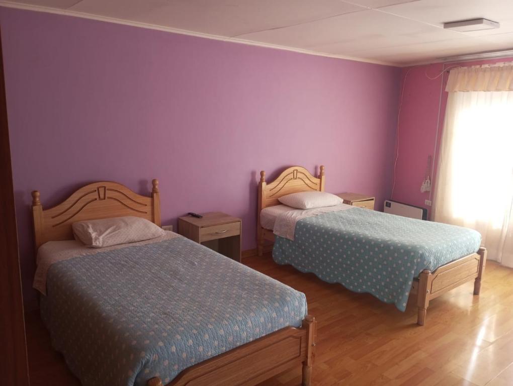 duas camas num quarto com paredes roxas em Hostal GoTravels em Calama