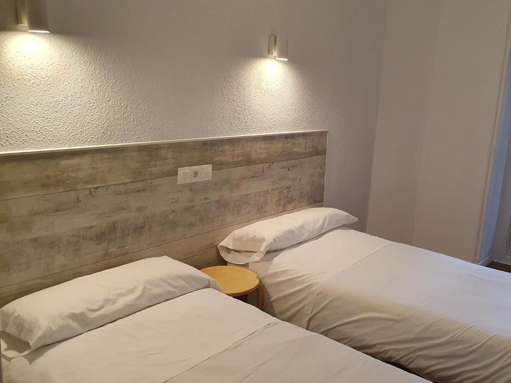 duas camas individuais num quarto de hotel com luzes em Hostal Ginebra em Madri
