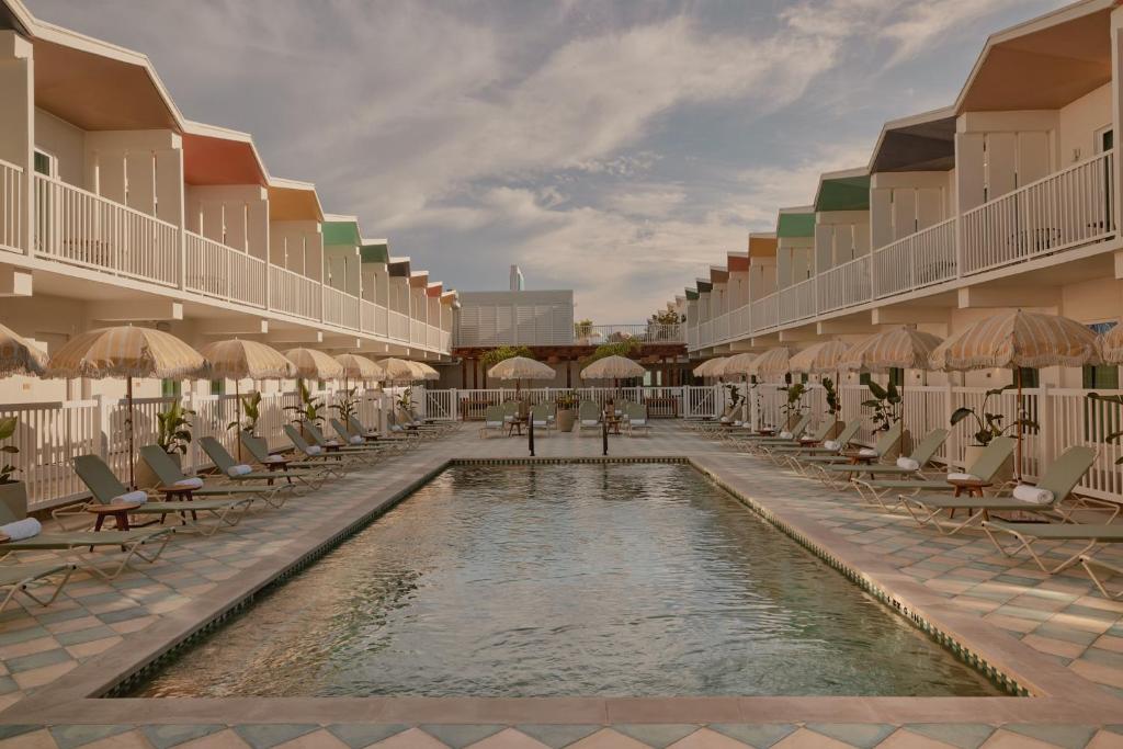 una piscina en un complejo con sillas y sombrillas en Hotel Lucine en Galveston