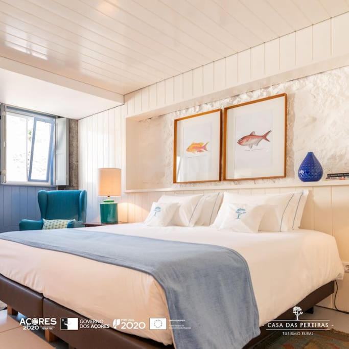 1 dormitorio con 1 cama grande y 1 silla azul en T2 Casa das Pereiras en Calheta de Nesquim