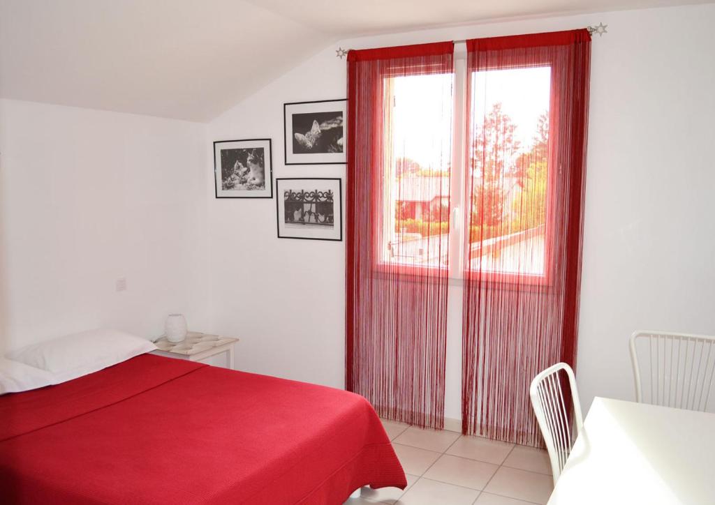een slaapkamer met een rood bed en een raam bij Chambre avec salle de bain privative comme à l'hôtel et "salon-cuisine" à partager avec les 4 autres locataires in Saint-Maurice-de-Gourdans