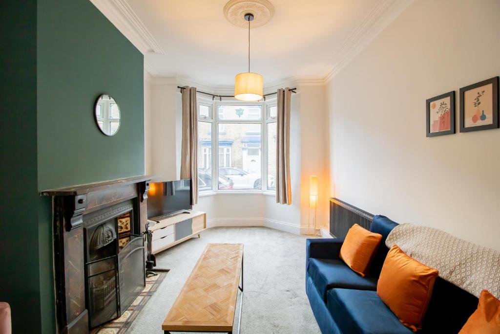 ein Wohnzimmer mit einem blauen Sofa und einem Fernseher in der Unterkunft Charming House - Perfect For Long Stays in Bishop Auckland