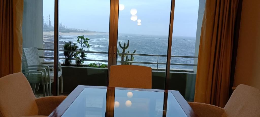 a table and chairs in a room with a view of the ocean at Matosinhos -Seas Apartment- Cabo das Marés in Matosinhos