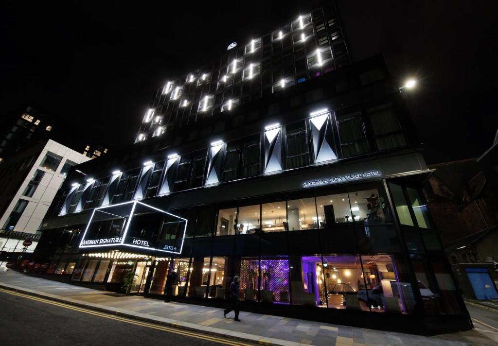 un edificio con una persona caminando delante de él por la noche en Sandman Signature Glasgow Hotel, en Glasgow