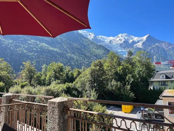 d'un balcon avec un parasol et une vue sur les montagnes. dans l'établissement Appart Centre Chamonix Grande Terrasse Mont Blanc, à Chamonix-Mont-Blanc