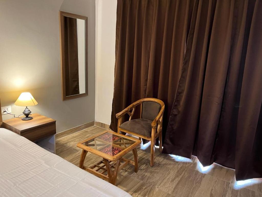 グレーター・ノイダにあるMurti Home Staysのベッドルーム1室(ベッド1台、椅子、ガラステーブル付)