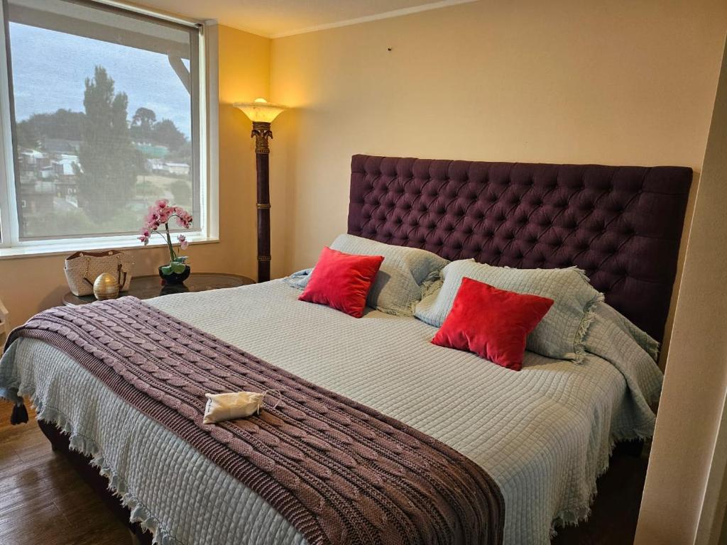 1 dormitorio con 1 cama grande con almohadas rojas en Departamento a minutos del Lago, en Puerto Varas