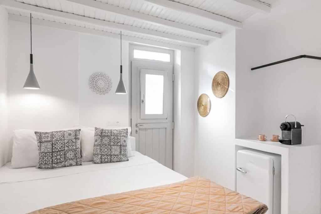 een witte slaapkamer met een bed en een raam bij August Mykonos in Mykonos-stad
