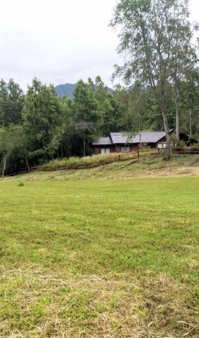 a house in the middle of a grass field at Casa campo en plena naturaleza 3 dormitorios y 2 baños in Lago Ranco